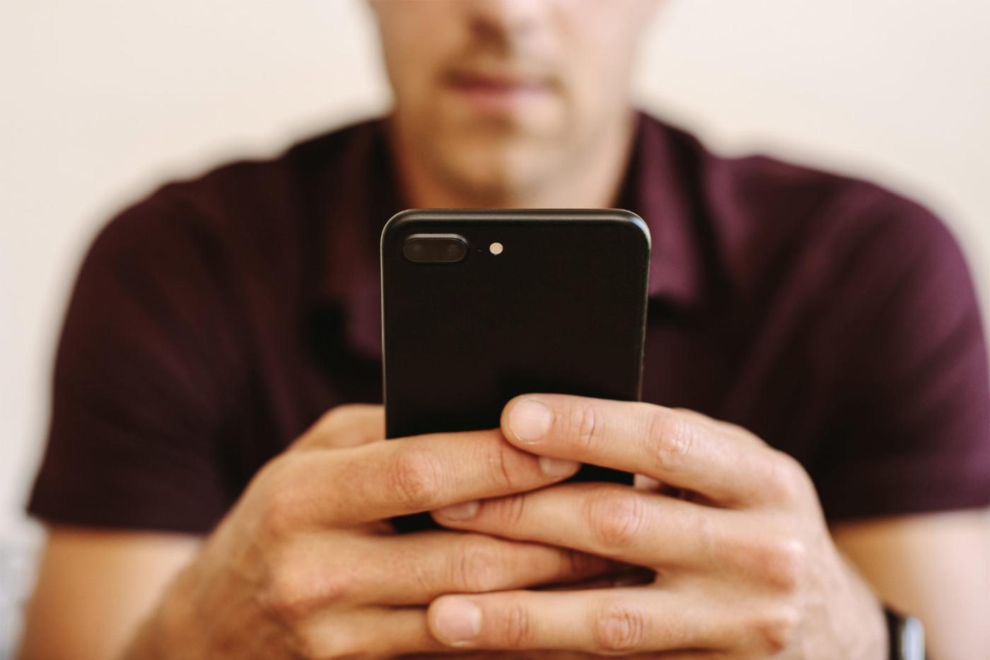 Persona sosteniendo un teléfono inteligente mientras navega por Internet, representando la función de Salida Rápida para abandonar el sitio web rápidamente.
