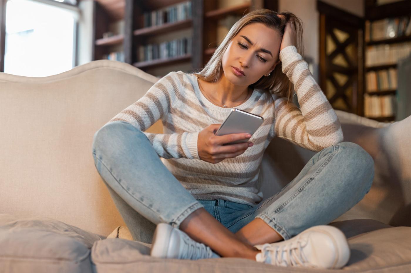 Concerned woman looking at her phone while seeking immediate help and support.